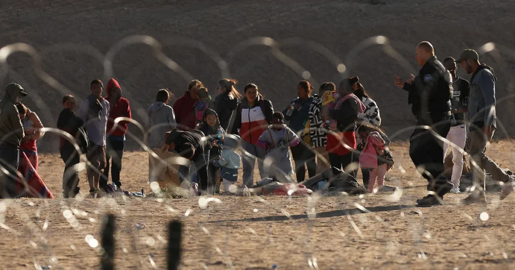 Migrant people wait on the banks of the Rio Grande to be processed by U.S. Border Patrol, after crossing from Ciudad Juarez, in El Paso, Texas,