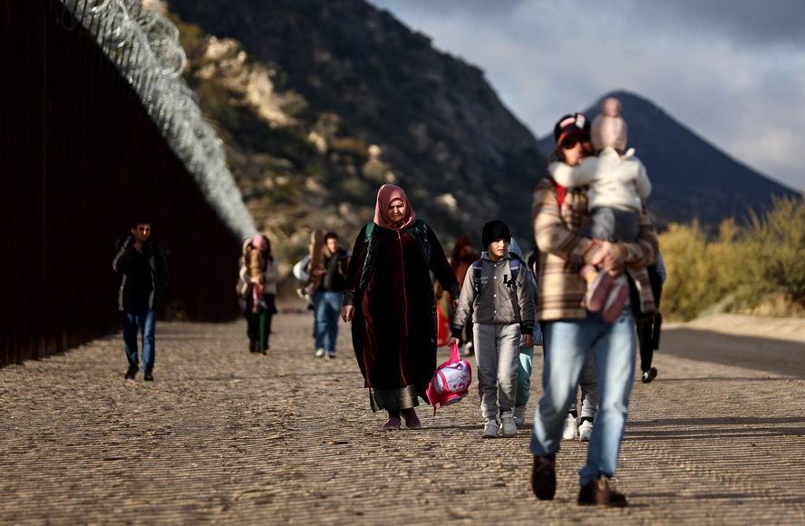Asylum seeking migrants from Tajikistan walk toward a makeshift camp to await processing by the U.S. Border Patrol on Friday in Jacumba Hot Springs, California.
